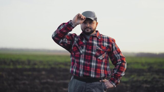 Portrait of villager standing alone in beautiful rural landscape, medium shot. Self-confident tractor driver of machinery technician posing in agricultural fields, adult farmer looking at camera