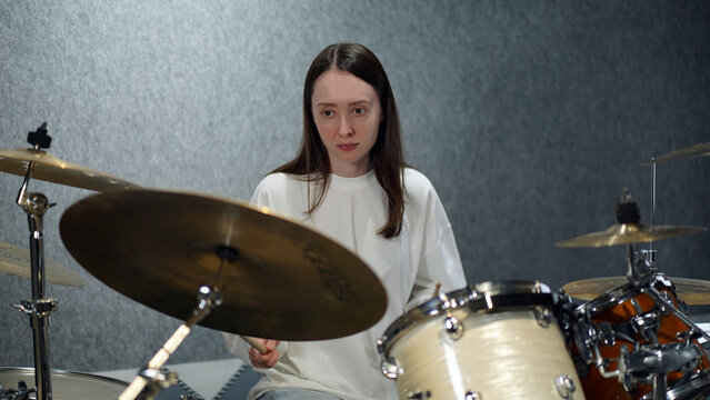 young woman playing drums in a studio, learning process, music