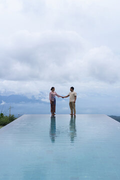 Balinese couple holding hands at infinity pool, Bali, Indonesia