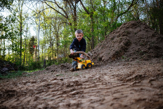 Young Boy Playing With Toy Loader Outdoors