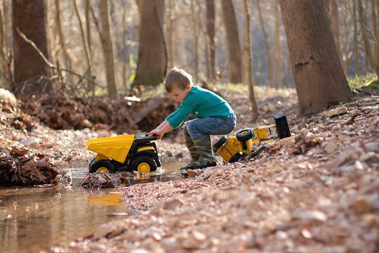 Child Playing With Toy Truck In Stream