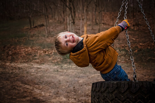 Smiling Child Hanging From Tire Swing