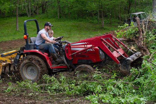 Father Driving Tractor With Child On Lap