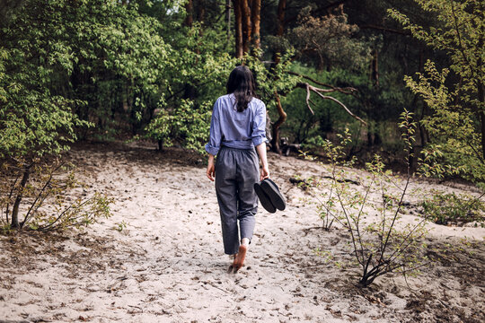 Person stands barefoot in forest with arms outstretched looking upward. inner peace journey, barefoot grounding technique, celebrating life moment.