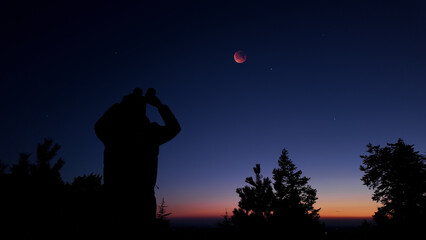 Fototapeta premium Amateur astronomer using binoculars for observing stars, planets, Moon and other celestial objects.