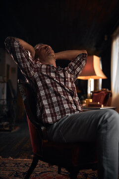 Man with headache, depression, sadness and loneliness sitting on a chair at home.