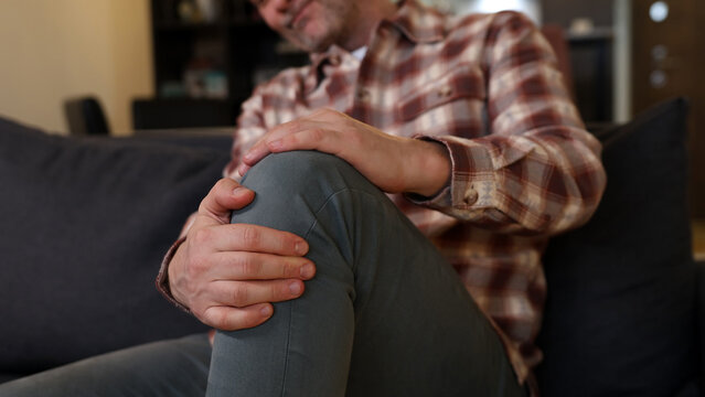 Man at home holding painful injured knee.
