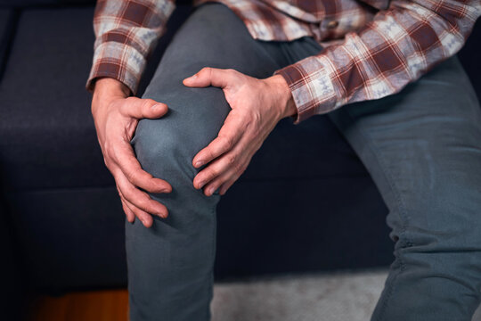 Man at home holding painful injured knee.