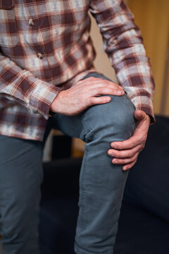Man at home holding painful injured knee.