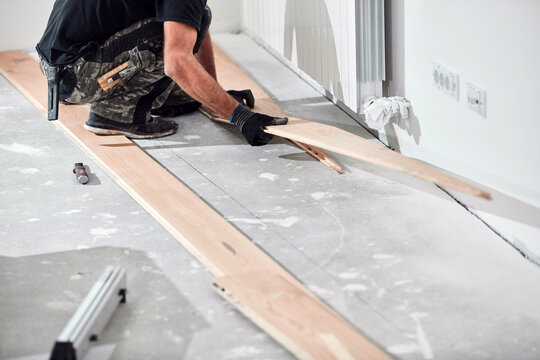 Professional handyman installing laminate flooring in a new apartment.
