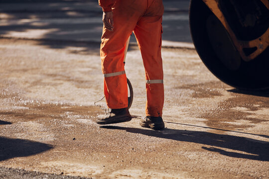 Construction worker using tape measure to measure dimensions of the street during reconstruction.