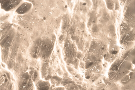 Transparent cosmetic gel, texture on a beige background, close-up.