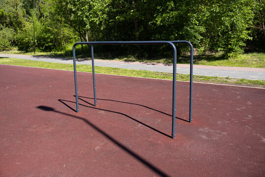 Metal parallel bars installed on a professional rubber safety surface in an outdoor fitness park, perfect for calisthenics.