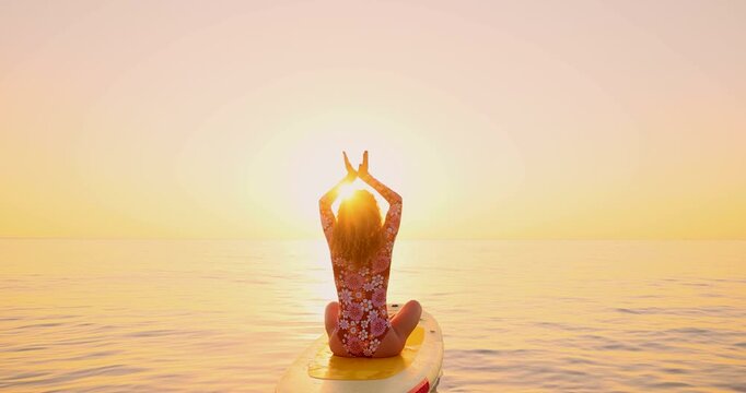 Happy young woman walking on a sup board by the sea during her summer vacation. Slow motion