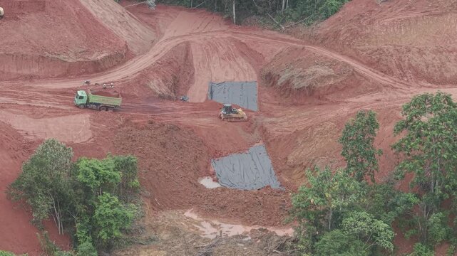 The activity of a crawler bulldozer leveling the fill soil transported by a truck for road construction