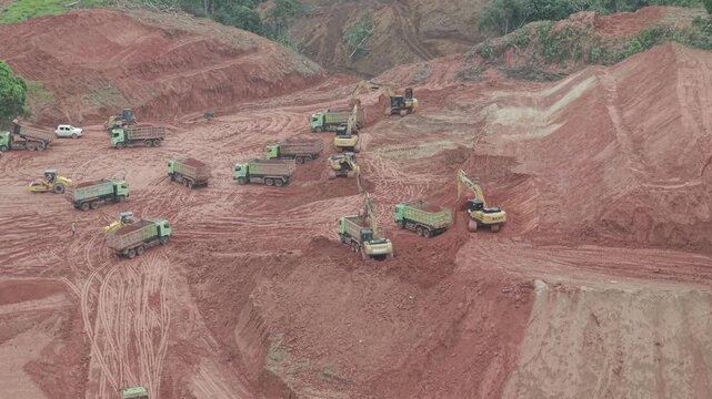 The busy trucks and excavators in road construction, opening new roads in the mountainous areas of Kalimantan