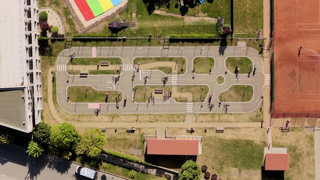 Aerial view of a traffic playground with children on bicycles, miniature road markings and green grass patches in Kyjov, South Moravian Region, Czechia.