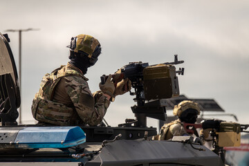 Fototapeta premium Special Forces Soldier Operating Mounted Machine Gun on Armored Military Vehicle During Tactical Combat Training Exercise