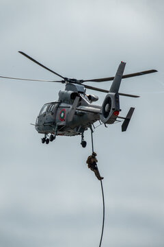 Elite special forces operator fast-roping from a hovering military helicopter during a tactical insertion or rescue mission