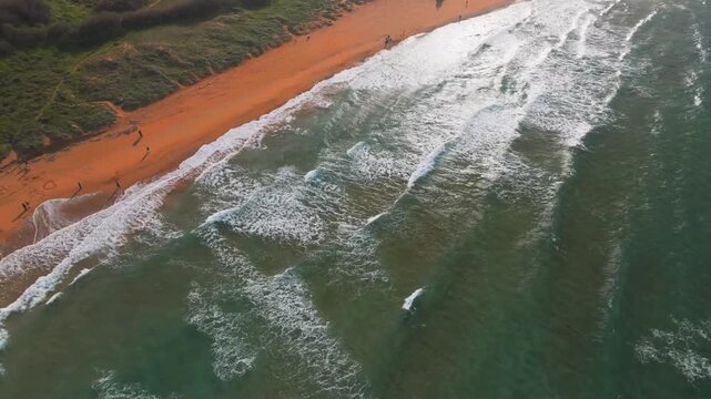 Drone panorama of Ramla bay, famous beach known for its unique golden-orange sand.