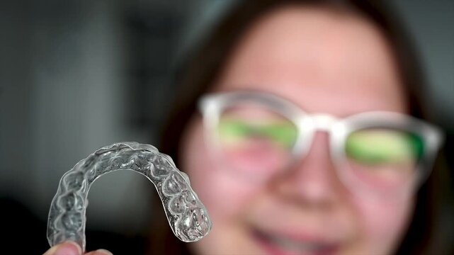 Teenager carefully placing transparent orthodontic aligner tray onto teeth at home, daily dental care routine and invisible braces treatment for adolescent patient