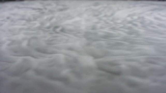 Circular black hockey puck glides across a smooth surface, leaving a trail of white powder as it moves, creating a dynamic visual effect in a low-light setting