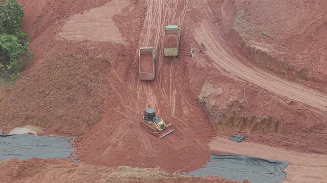 A crawler bulldozer is leveling the fill soil unloaded from a truck for road construction