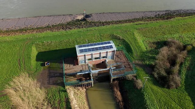 Aerial view of industrial pumping station discharge and water flow into a rural Lincolnshire river.