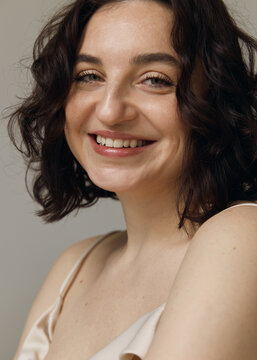 A studio portrait of a beautiful girl with curly hair and a lovely smile 