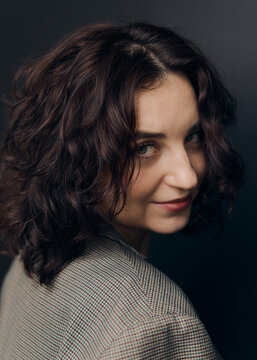 A studio portrait of a beautiful girl with curly hair and a lovely smile 