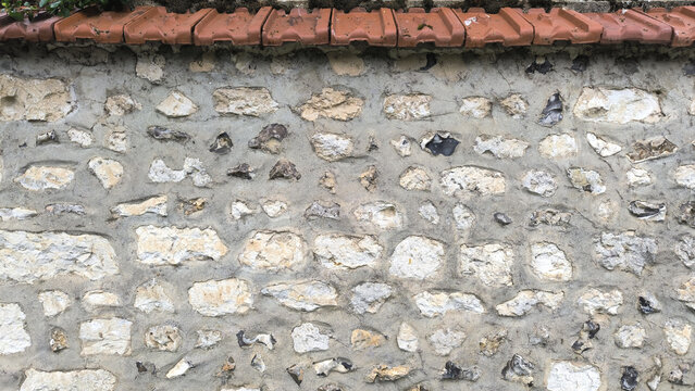 Traditional Normandy Rubble Stone and Flint Wall with Terracotta Roof Tile Coping in a French Village Street