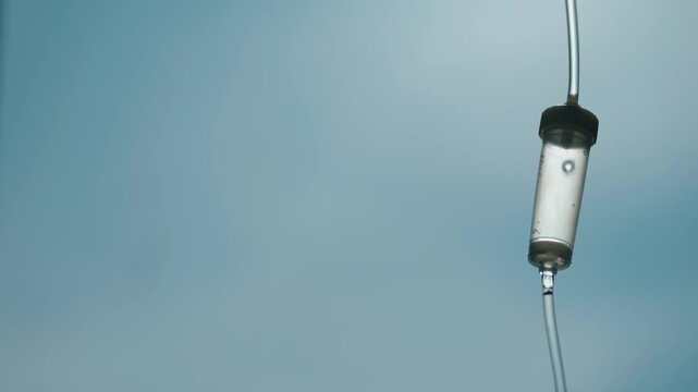IV drip infusion drop falling in slow motion against a soft blue background.