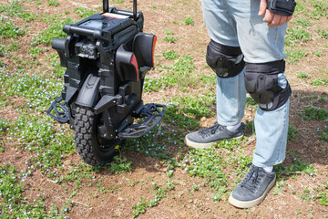 A man stands next to an electric unicycle in park. © TATIANA KIM