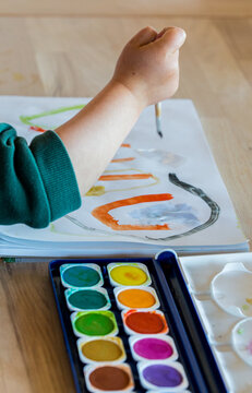 Toddler painting with watercolors and brush, close-up, hand only