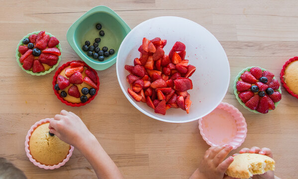 Children decorating a homemade cake with berries, close-up, baking with children