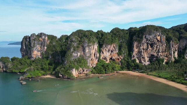 Krabi, Thailand : Aerial drone footage of boat leaves tonsai beach in Railay of Andaman coastline in Krabi, Thailand. Famous for rock climbing area surrounded by limestone cliff