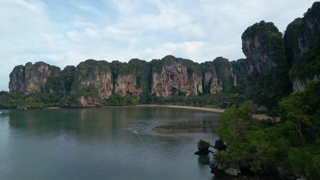 Krabi, Thailand : Aerial revealing drone footage of the dramatic Tonsai beach in Railay along the Andaman coastline in Krabi province in southern Thailand at low tide during the rainy season.