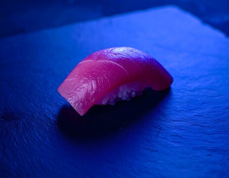 Nigiri de at&uacute;n servido sobre plato oscuro con iluminaci&oacute;n azul en una presentaci&oacute;n minimalista de sushi
