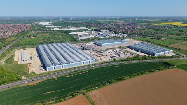 Aerial view of Symmetry Park, Kettering featuring large industrial warehouses and distribution centers next to a highway and green fields Pytchley, England, United Kingdom.