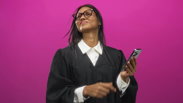 Woman judge pointing finger at smartphone, visible hand tapping screen while wearing black judicial robe and glasses in studio; curiosity authority.