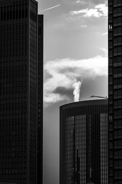 Steam rises between Frankfurt skyscraper walls in black and white, where tower architecture and urban contrast tighten the skyline under clouds