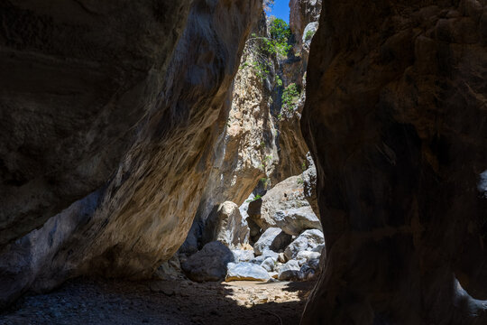 Deep canyon landscape with towering rock formations and boulders on a sunny day