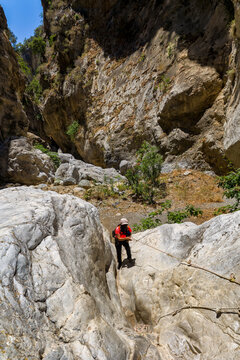 Female hiker using a rope to descend rocky Sarakina Gorge in Crete, Greece