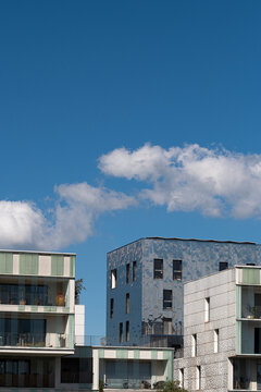 Lyon architecture in La Confluence rises beneath blue sky and clouds, where residential buildings and facade textures shape an urban view in France