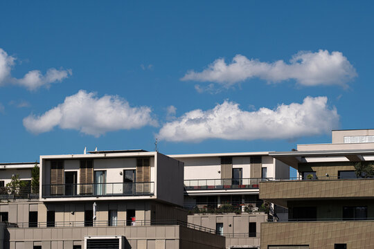 Lyon residential buildings in La Confluence align below blue sky and clouds, where architecture and facade planes define an open urban horizon in France