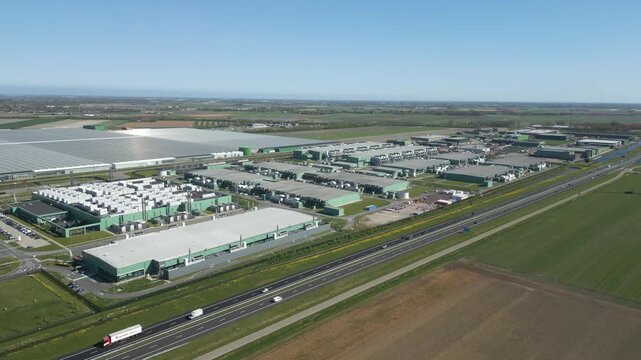 Wide aerial footage of a large industrial technology and datacenter campus next to highways and agricultural fields in the Netherlands.