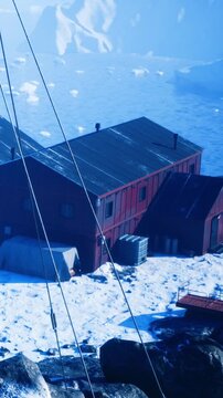 Nestled in a frozen landscape, a striking red cabin stands alone among the snow. Gentle blue tones envelop the scene, creating a serene atmosphere of winter solitude and adventure.