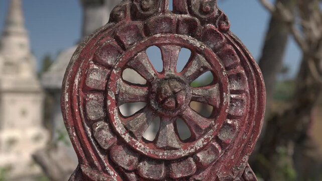 Slow moving close up of a red dharma wheel ornament at a Buddhist temple on Don Khon, Laos, with shallow focus.