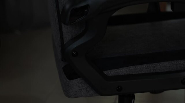 Close-up static shot of hands using an allen wrench to tighten a gaming chair backrest during furniture assembly