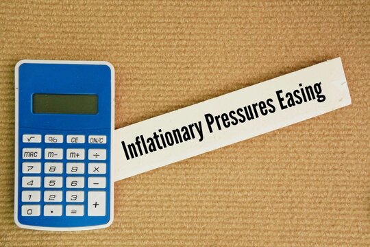 Calculator and paper with the words Inflationary Pressures Easing. the forces causing prices to rise in an economy are weakening, leading to a slower rate of inflation.